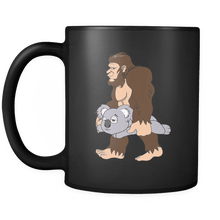 Load image into Gallery viewer, RobustCreative-Bigfoot Sasquatch Carrying Koala - I Believe I&#39;m a Believer - No Yeti Humanoid Monster - 11oz Black Funny Coffee Mug Women Men Friends Gift ~ Both Sides Printed
