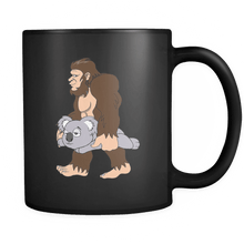 Load image into Gallery viewer, RobustCreative-Bigfoot Sasquatch Carrying Koala - I Believe I&#39;m a Believer - No Yeti Humanoid Monster - 11oz Black Funny Coffee Mug Women Men Friends Gift ~ Both Sides Printed
